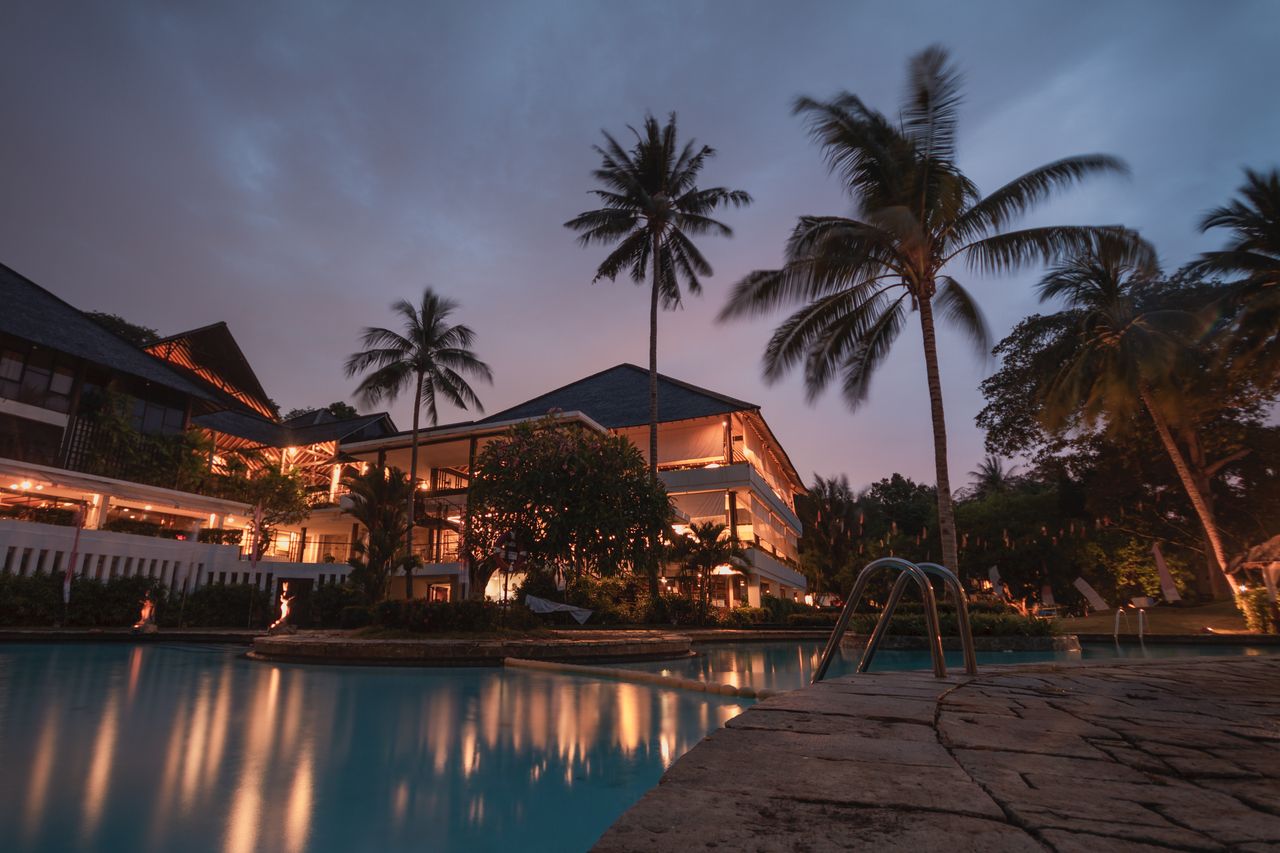 services-01 Luxurious tropical resort with swimming pool and palms at dusk, perfect for a tranquil vacation.
