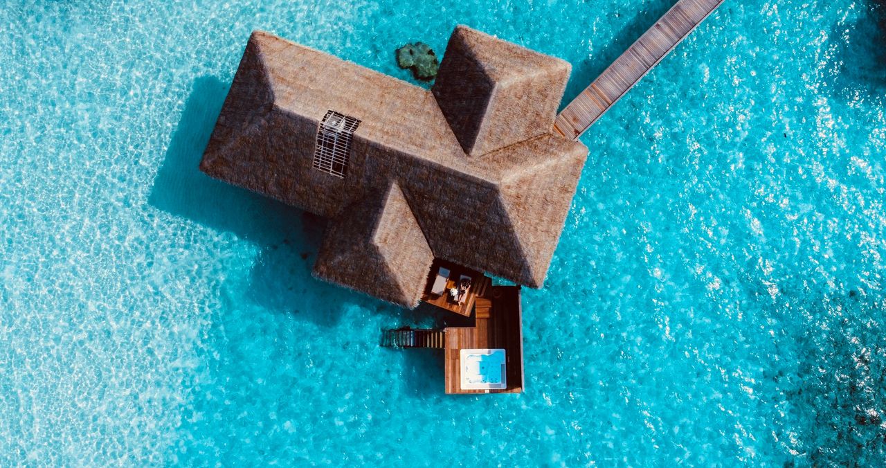 gallery-2 A stunning aerial view of a luxurious overwater villa in the Maldives surrounded by crystal clear blue waters.